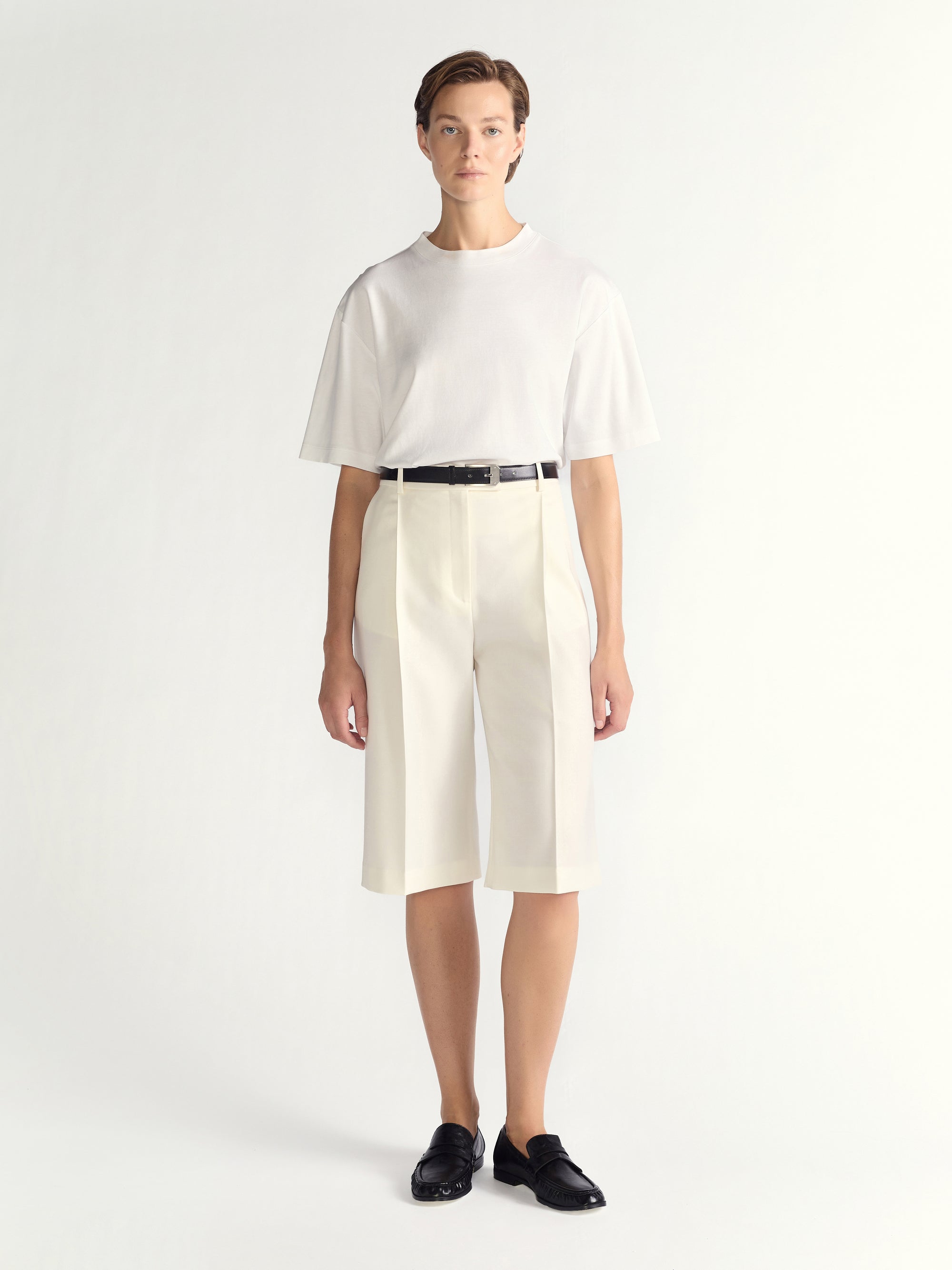 Person wearing a white outfit with a black belt on a white background