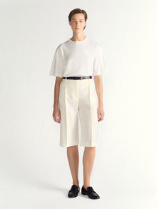 Person wearing a white outfit with a black belt on a white background