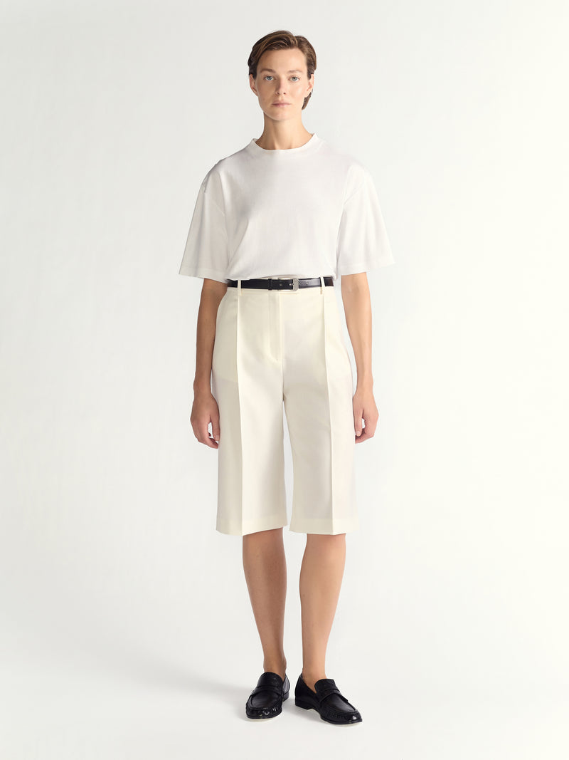 Person wearing a white outfit with a black belt on a white background