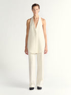 Woman wearing a white sleeveless top and pants on a white background