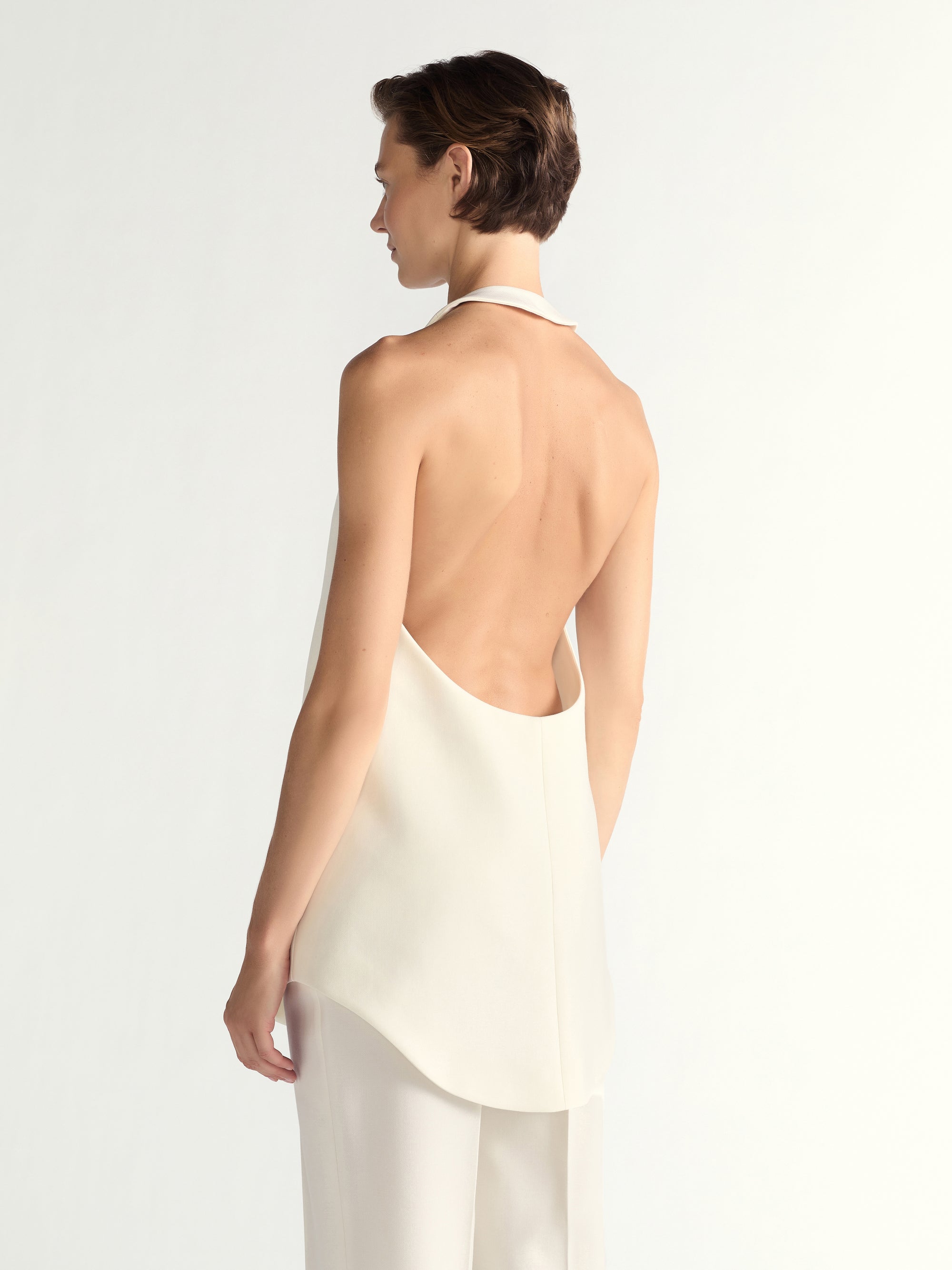 Woman wearing a white halter top and pants on a light gray background