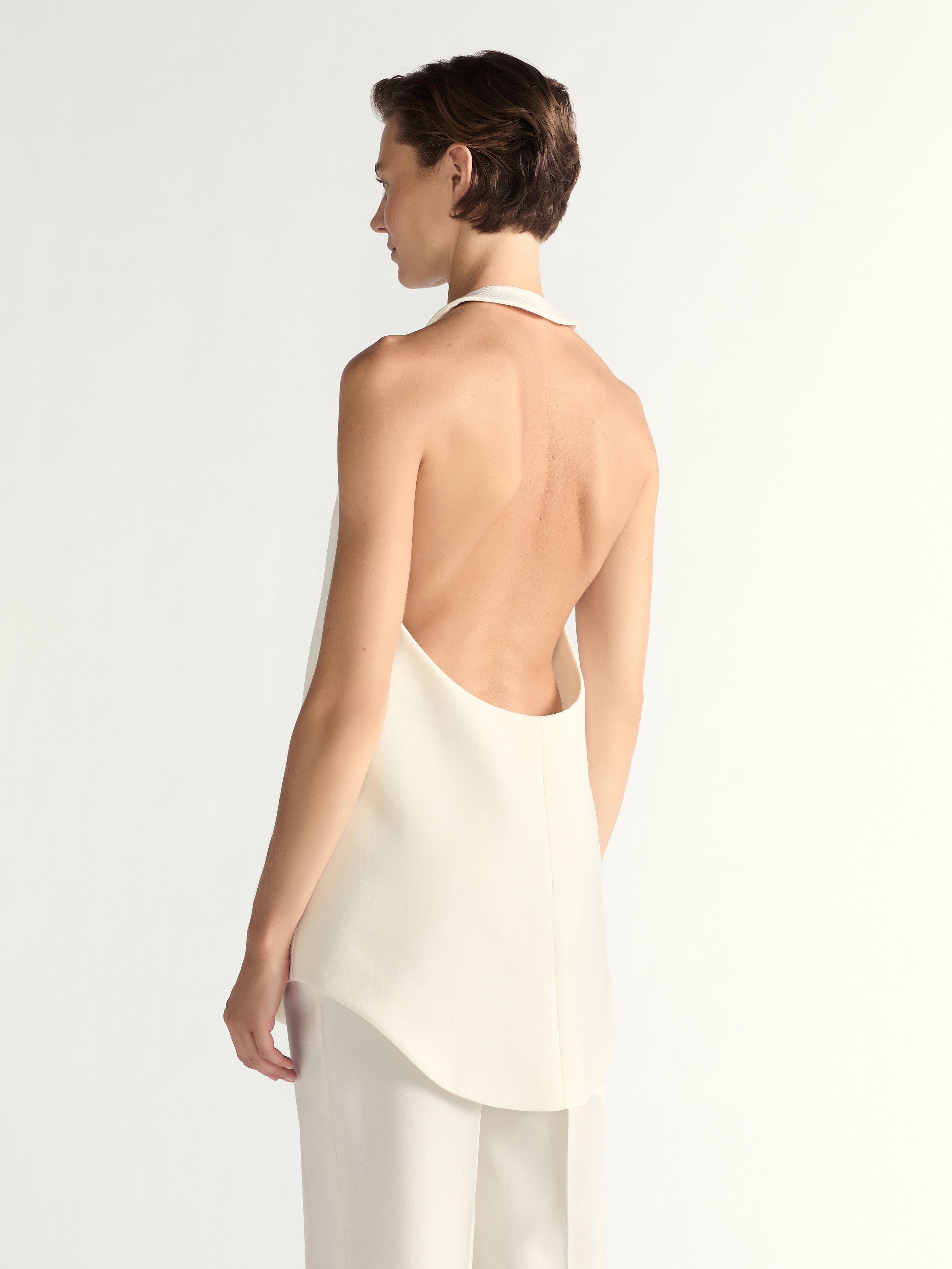 Woman wearing a white halter top and pants on a light gray background