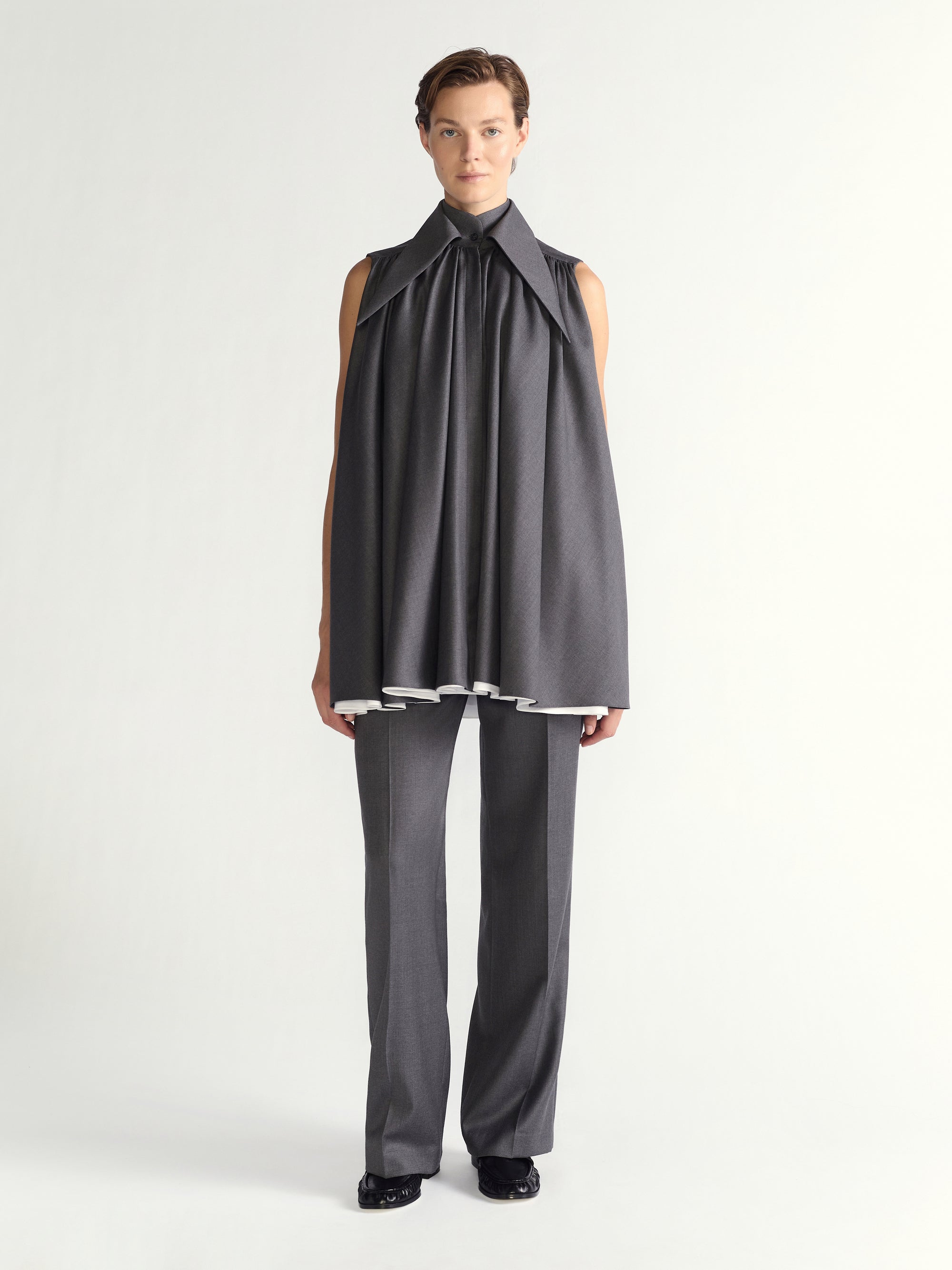 Person wearing a gray sleeveless dress and pants on a white background