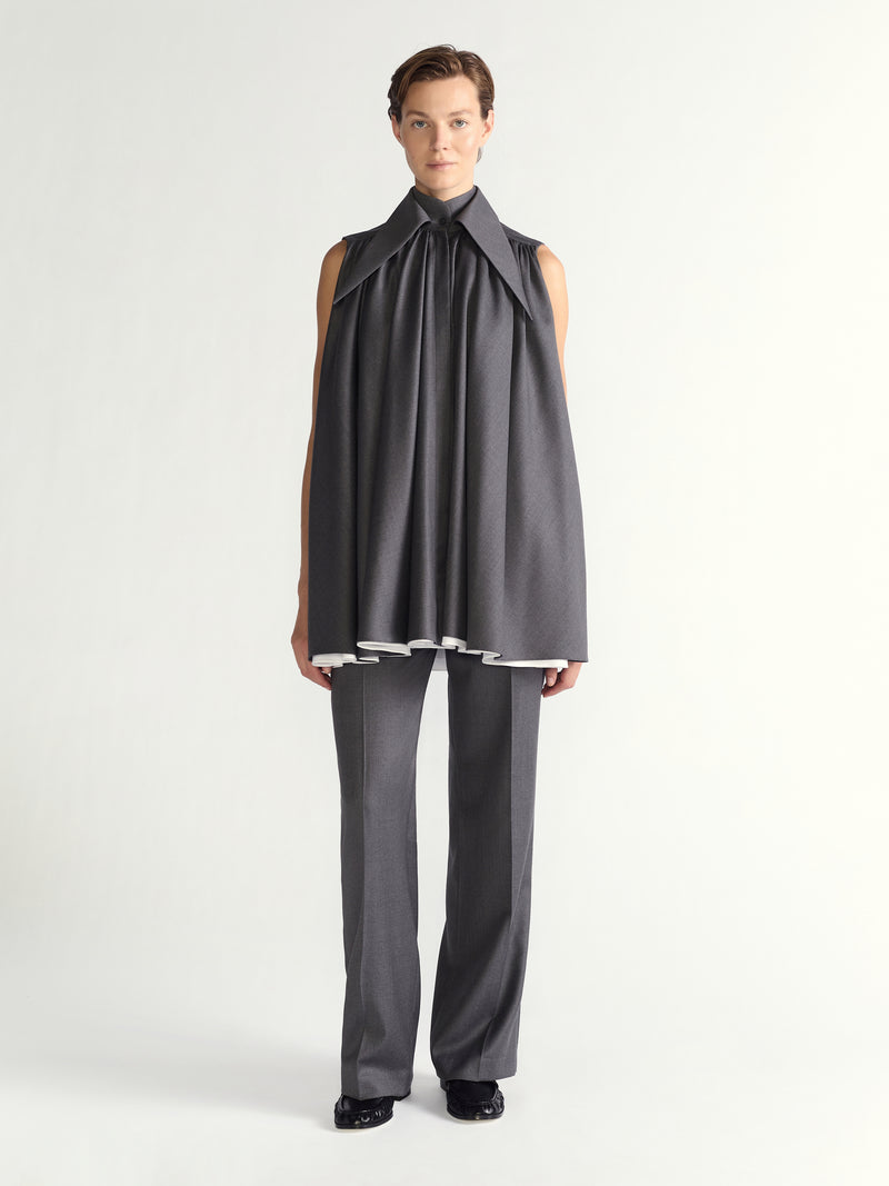 Person wearing a gray sleeveless dress and pants on a white background