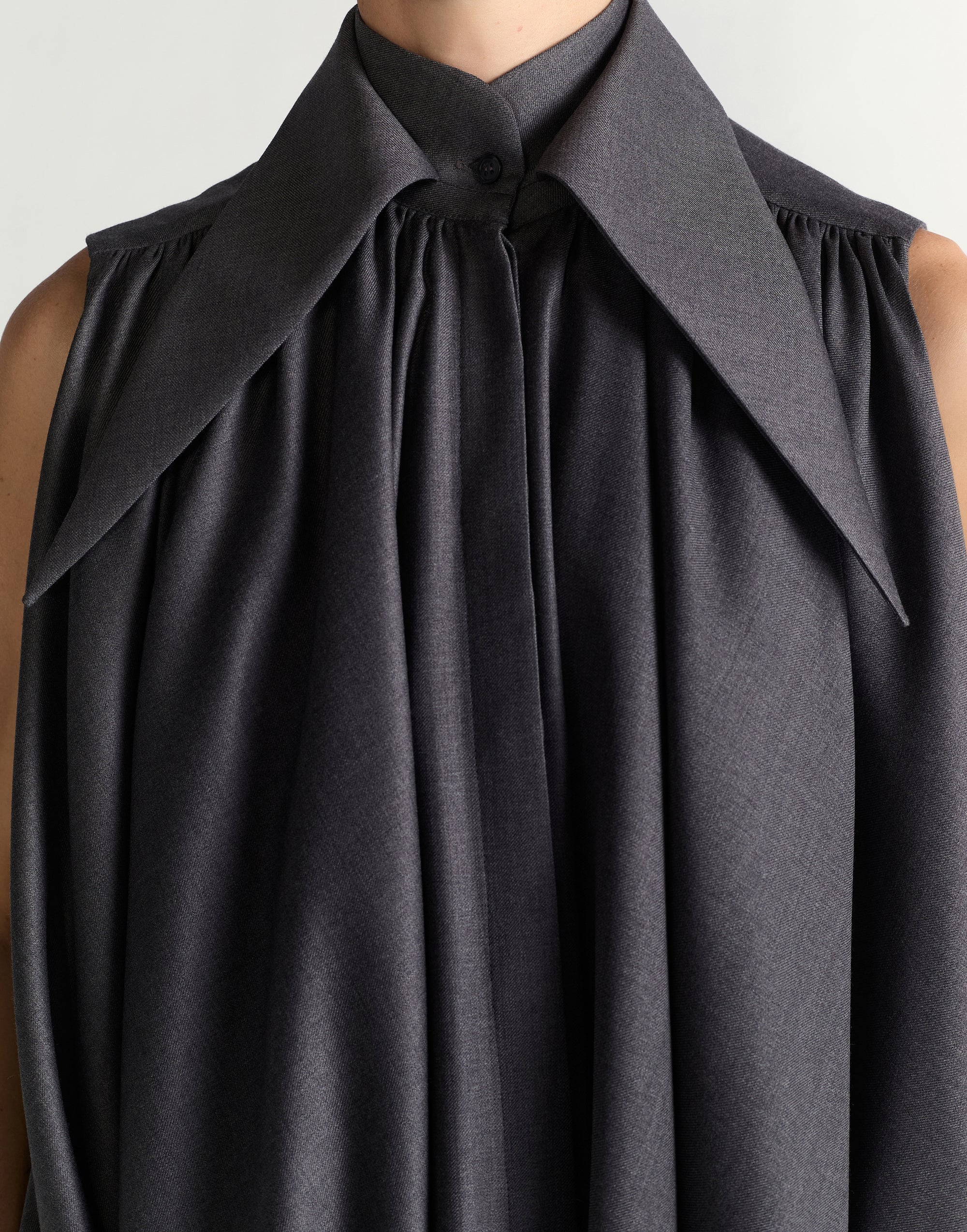 Black sleeveless dress with a large collar on a neutral background