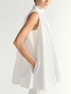 White sleeveless dress worn by a person on a plain background